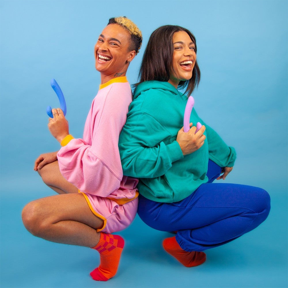 Two joyful people holding Jix vibrators, representing inclusive pleasure and connection with Cute Little Fuckers toys.