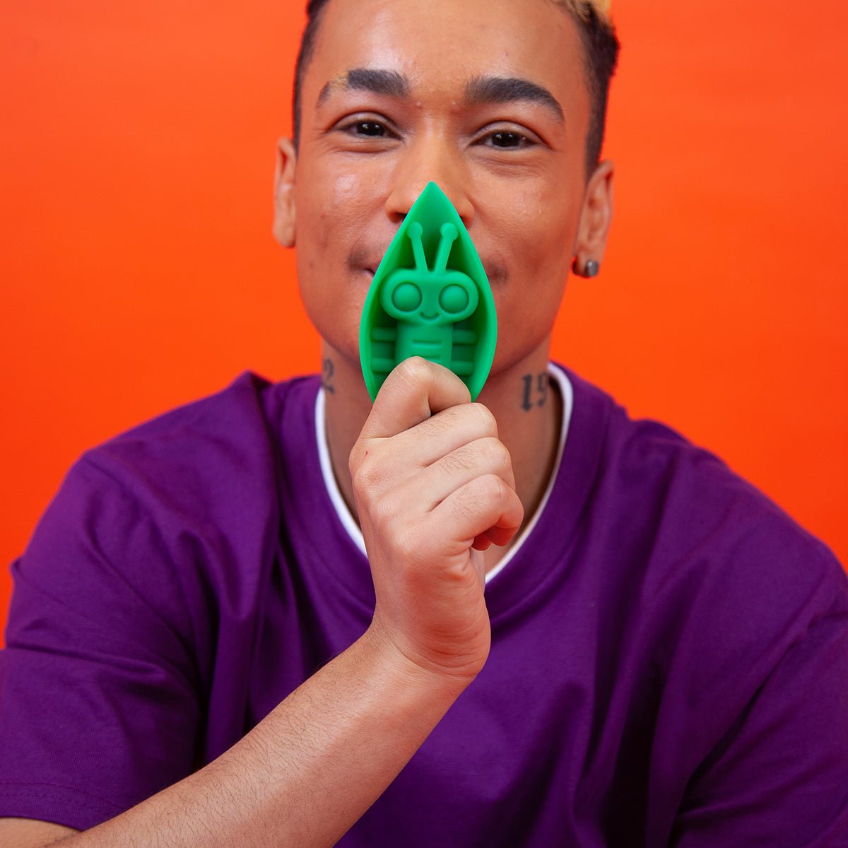 Zeep vibrator in Emerald color held near the face of a smiling person, showcasing joy and pleasure with this gender-inclusive toy