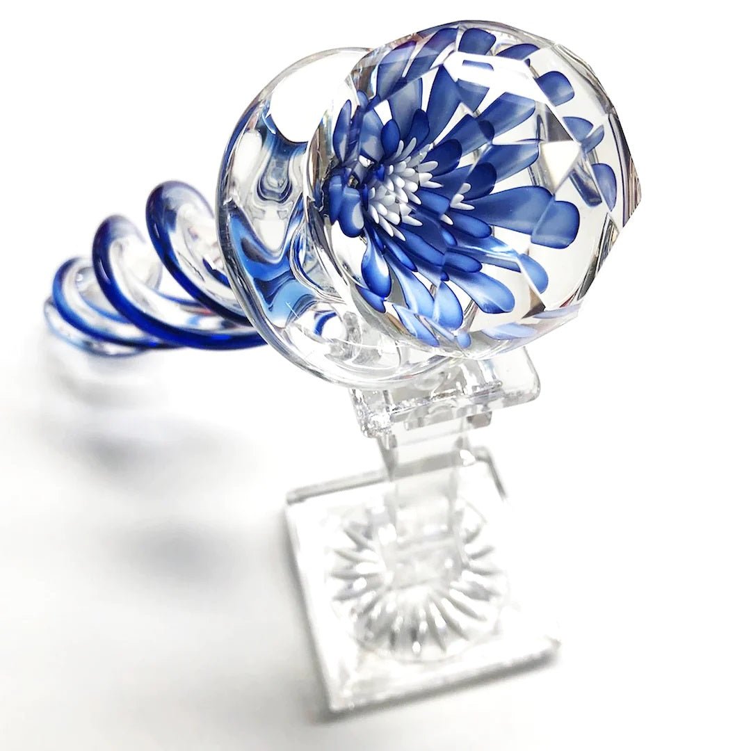 Crystal Delights Faceted Implosion Twist Glass Dildo propped up on a stand on a plain white background showcasing its twisted design. Available at SugarX in the Dildo section of the Sex Toys collection.