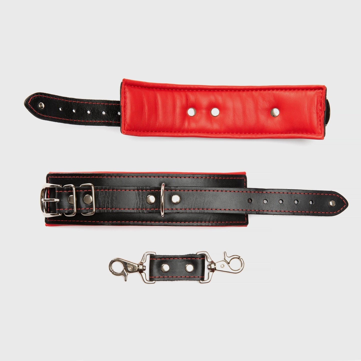 Close-up of Black and Red Mercer Padded Wrist Cuffs, showcasing the bold red lining and durable nickel hardware for BDSM play at SugarX.