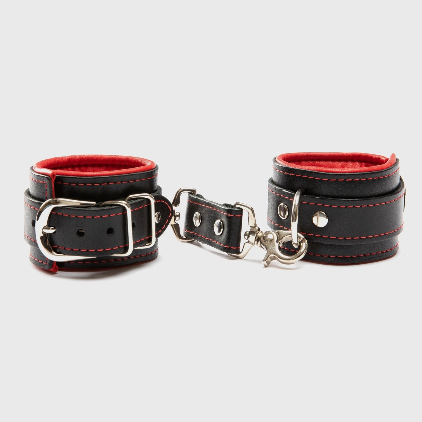 Close-up of Black and Red Mercer Padded Wrist Cuffs, showcasing the bold red lining and durable nickel hardware for BDSM play at SugarX.