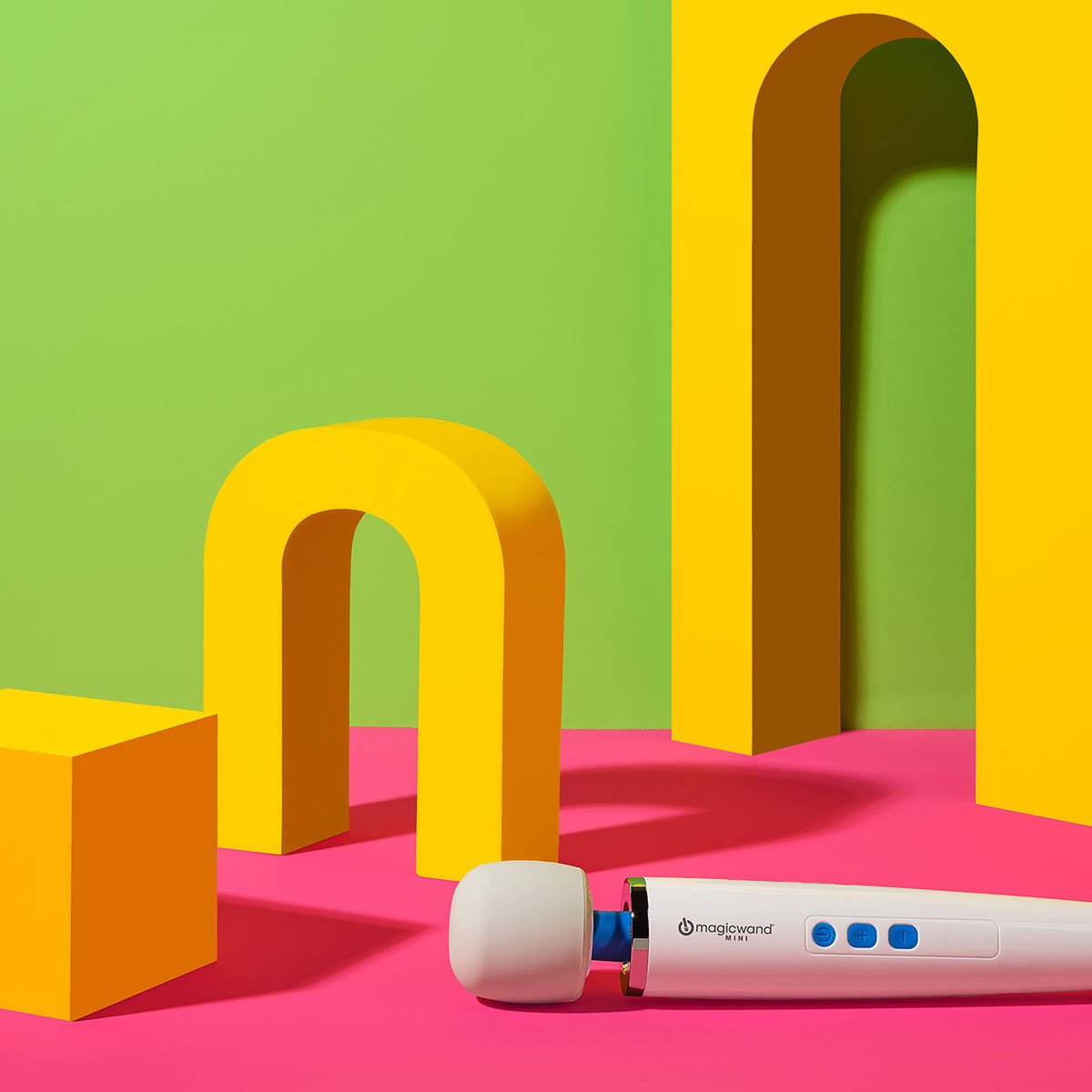 Magic Wand Mini Rechargeable vibrating wand sex toy lying on a colorful background. Available at SugarX in the Vibrating Wand section of the Sex Toy collection.