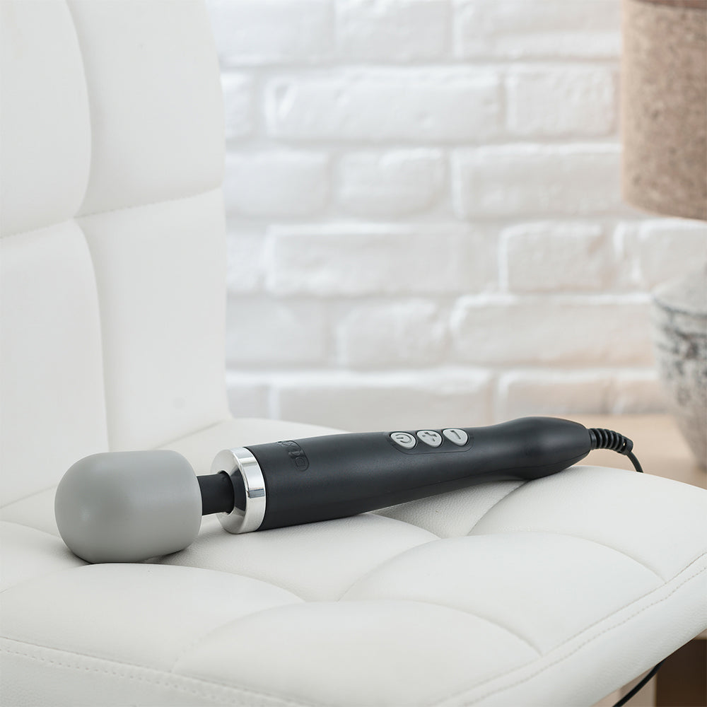 Doxy Original Massager wand vibrator lying on a couch. Available at SugarX in the Vibrators Collection.